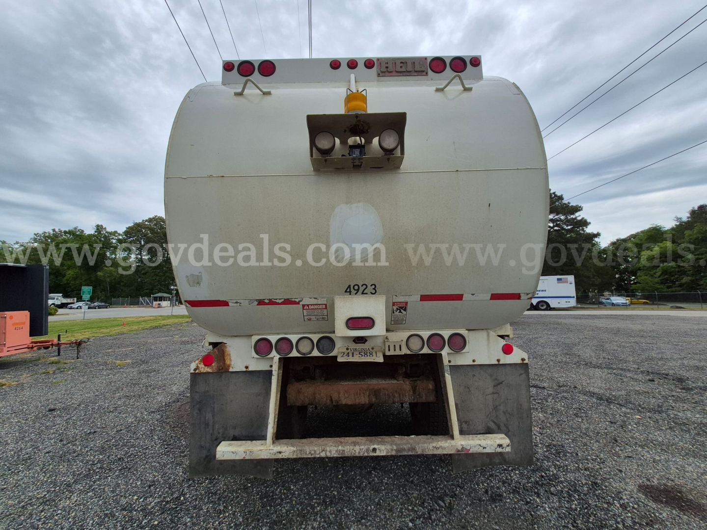 Back view of a white International 7400 trash truck tank showing rear lights and bumper with various small labels and a metal ladder/step structure.