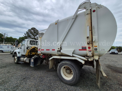 2017 International 7400 garbage truck side/back view showing large white waste body, rear hydraulic lift, wheel, and cab area.