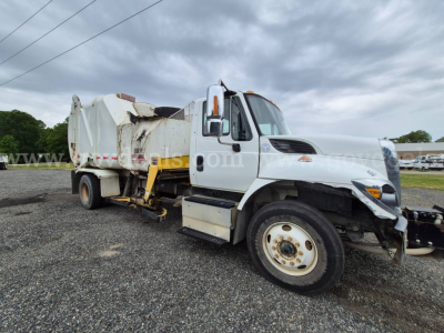 International 7400 garbage truck in-service showing front grille and side view with attached refuse body and hydraulic components.