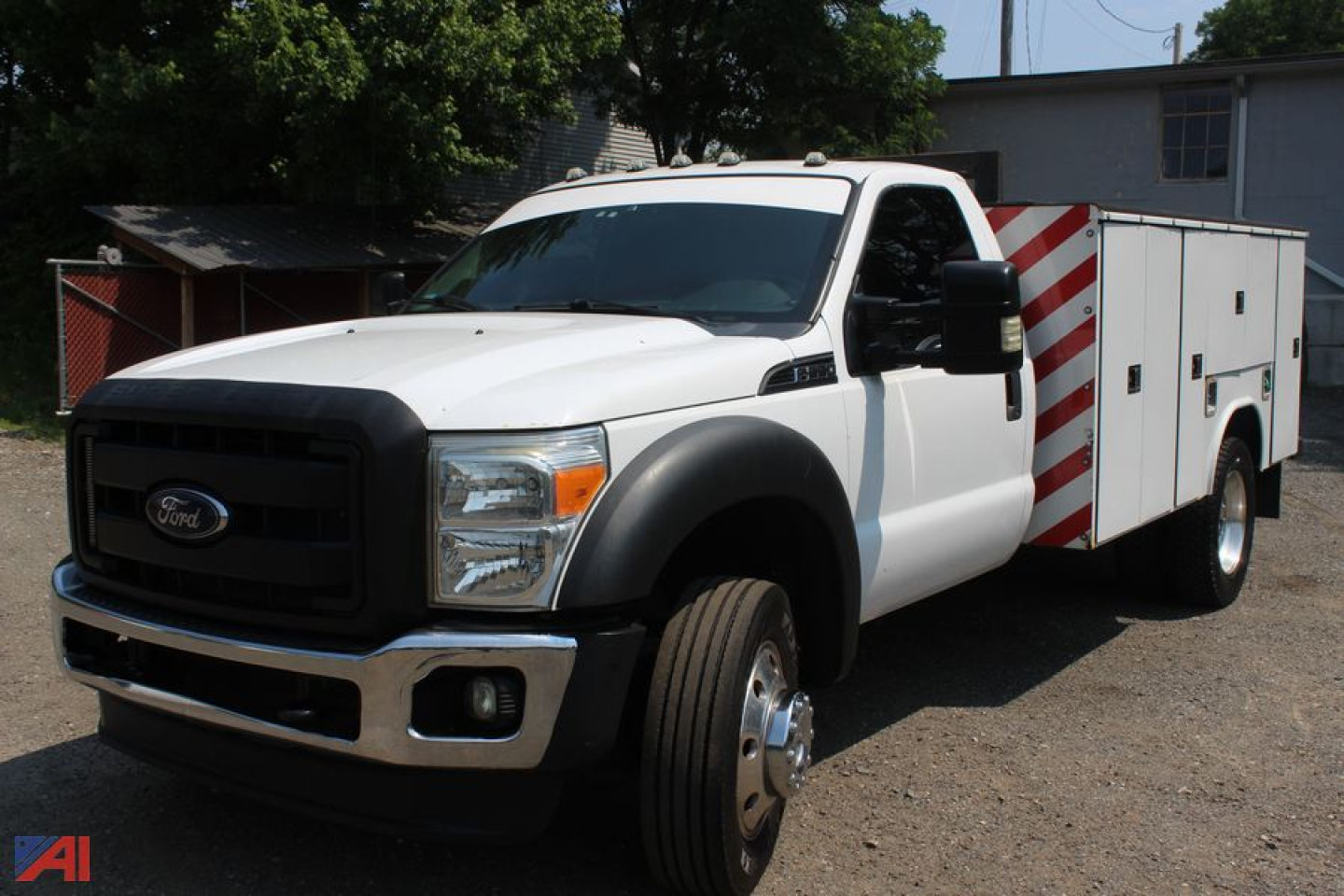 Ford F-550 Super Duty utility truck with service body, front grille and headlights visible, cab white, utility compartments to rear, red-and-white striped panels on the sides.