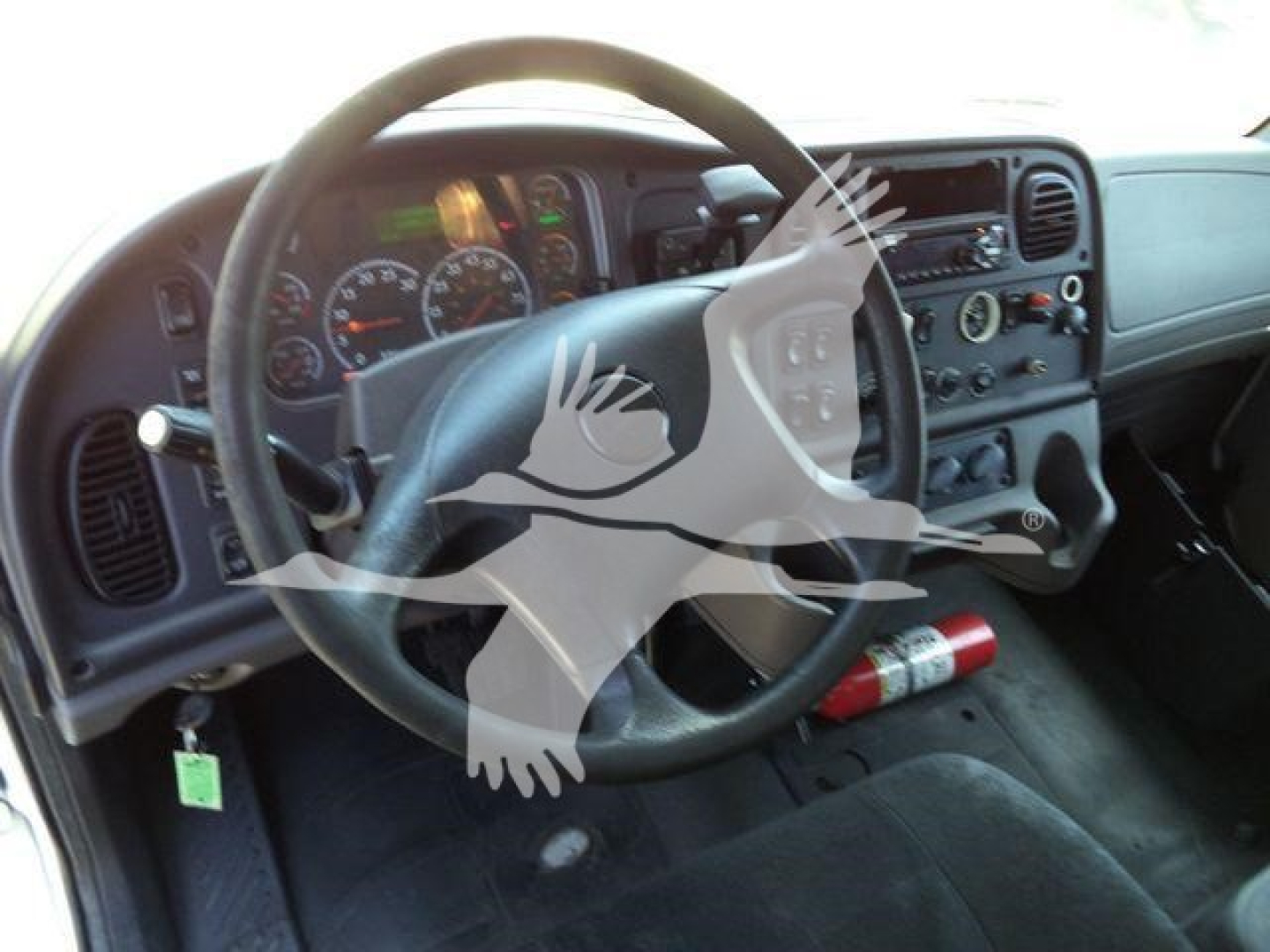 Dashboard and steering wheel view of a Freightliner M2 interior with gauges, steering wheel, and center console visible.