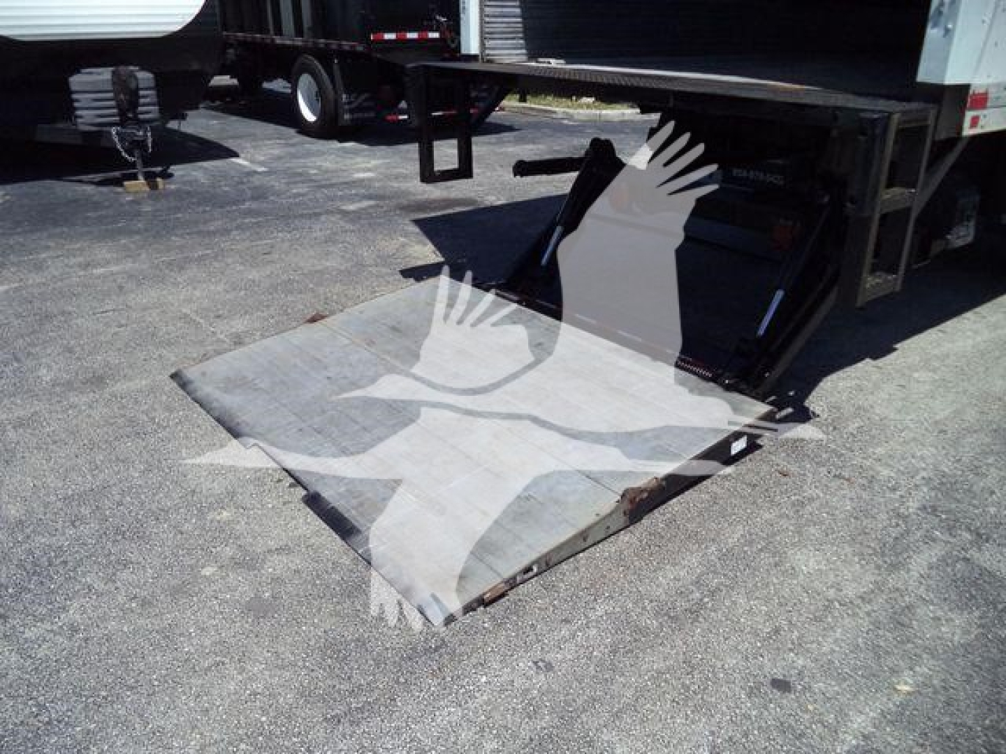 Forklift-style loading ramp attached to Freightliner M2 106 trailer showing metal ramp plate and rear undercarriage.