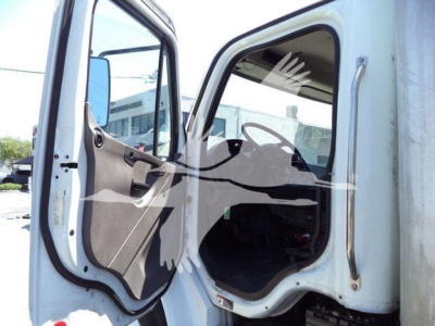Truck cab interior visible through open door of Freightliner M2 106, steering wheel and dashboard silhouette in view.