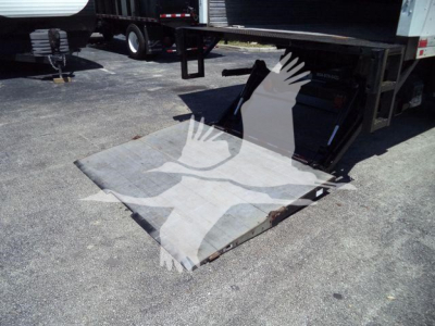 Forklift-style loading ramp attached to Freightliner M2 106 trailer showing metal ramp plate and rear undercarriage.