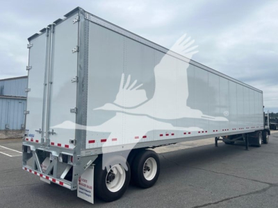 Trailer side view showing a 2027 Vanguard Vxp Plate Van, long gray trailer with white eagle artwork, dual rear wheels, no visible cab; stock VM605628.