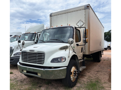 Freightliner M2 106 business class box truck front-left view showing white cab and box trailer in a used-truck lot; chrome bumper, grille, and side mirrors visible.