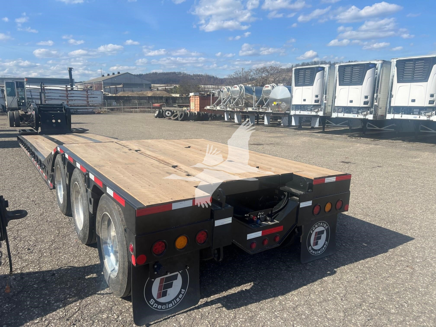 Lowboy trailer with wooden deck and triple-axle setup, Fontaine 55 PVR Pro, rear view showing dual wheels and rear lights.
