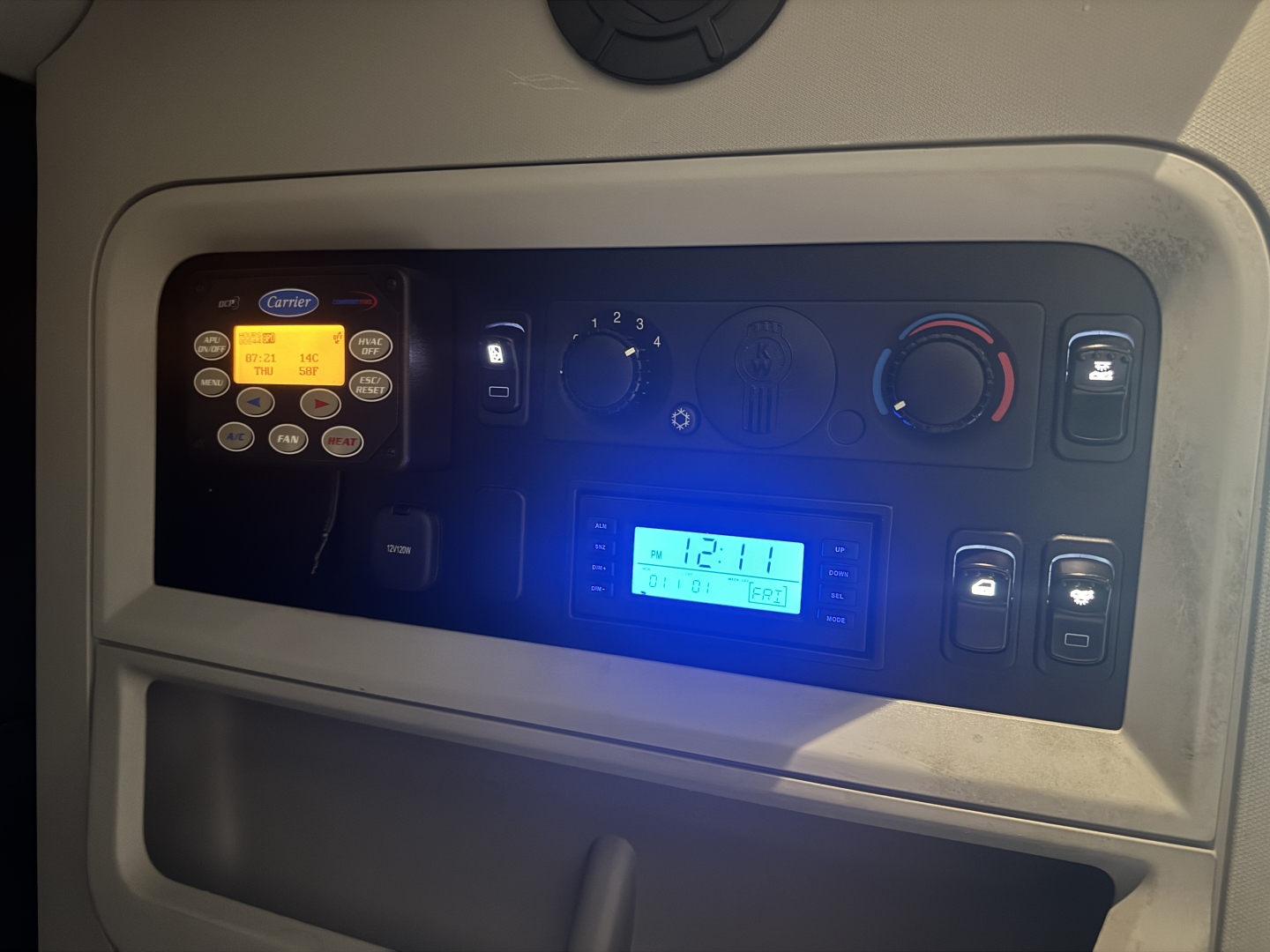 Kenworth T680 interior dash displaying control panel with CB radio, climate controls, and blue lit display.