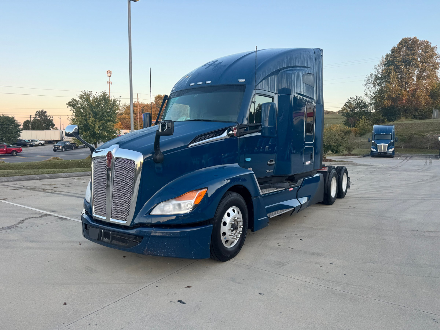 Kenworth T680 tractor in blue, three-quarter view with sleeper cab, dual rear axles, front grille and headlights visible.