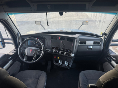 Truck cab interior view of a Kenworth T680 showing steering wheel, dashboard with gauges, central control panel, and gear shifters.