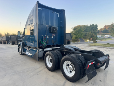 Kenworth T680 tractor rear left view showing dual rear axles, blue cab, and trailing equipment; no license plate visible.