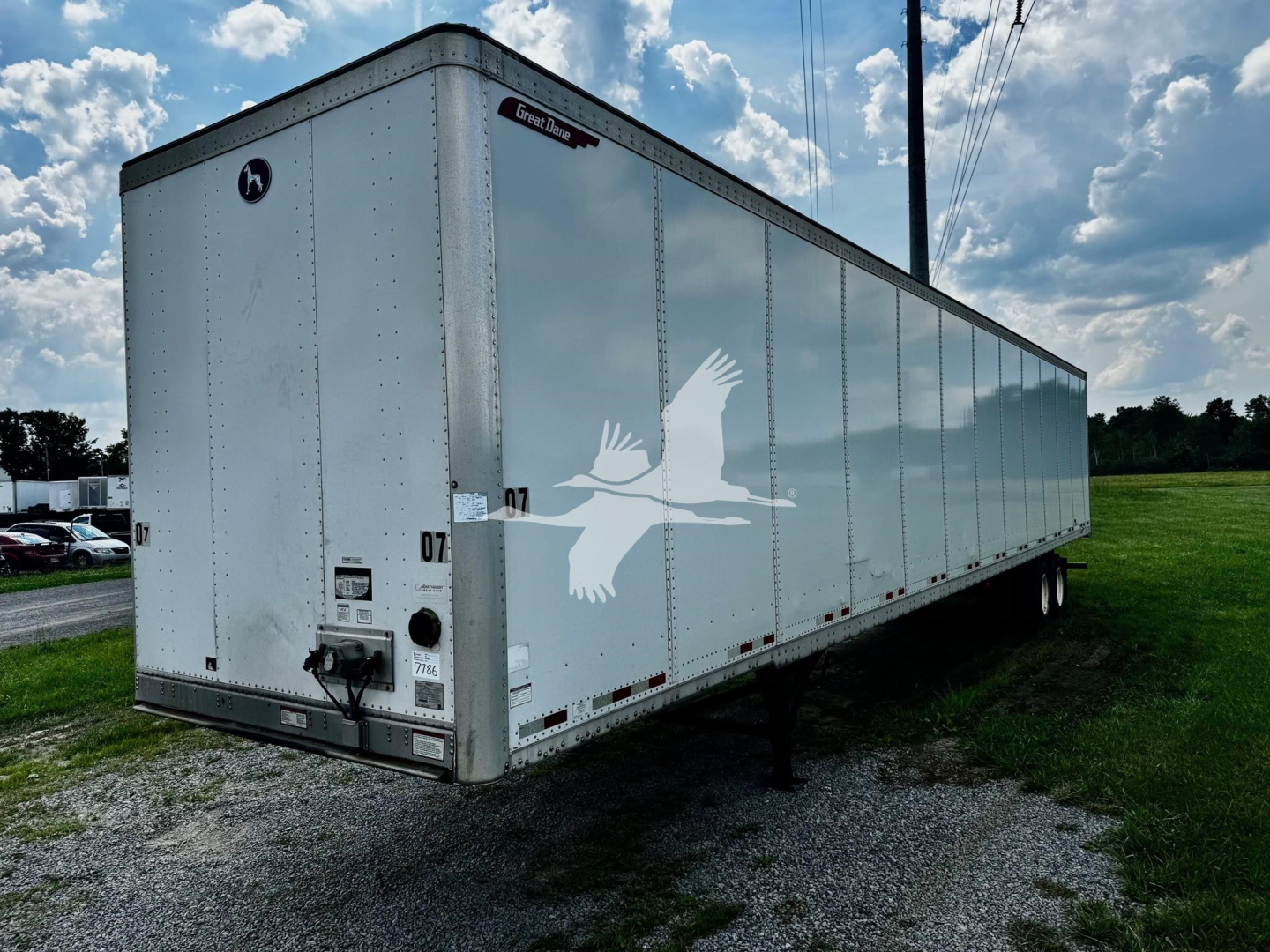 Great Dane plate van trailer showing white exterior with black trim and logo, side view with landing gear and wheels, VIN tag and stock number area visible.