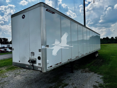 Great Dane plate van trailer showing white exterior with black trim and logo, side view with landing gear and wheels, VIN tag and stock number area visible.