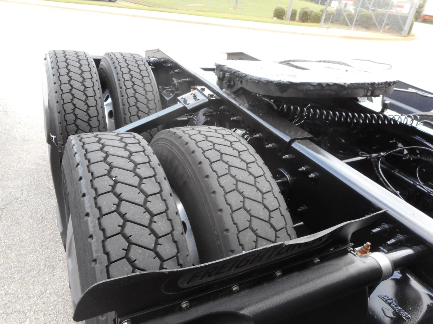 Tractor-trailer rear chassis with dual rear axles and tires, Freightliner Cascadia 126 chassis view showing tandem axle setup and frame rails.