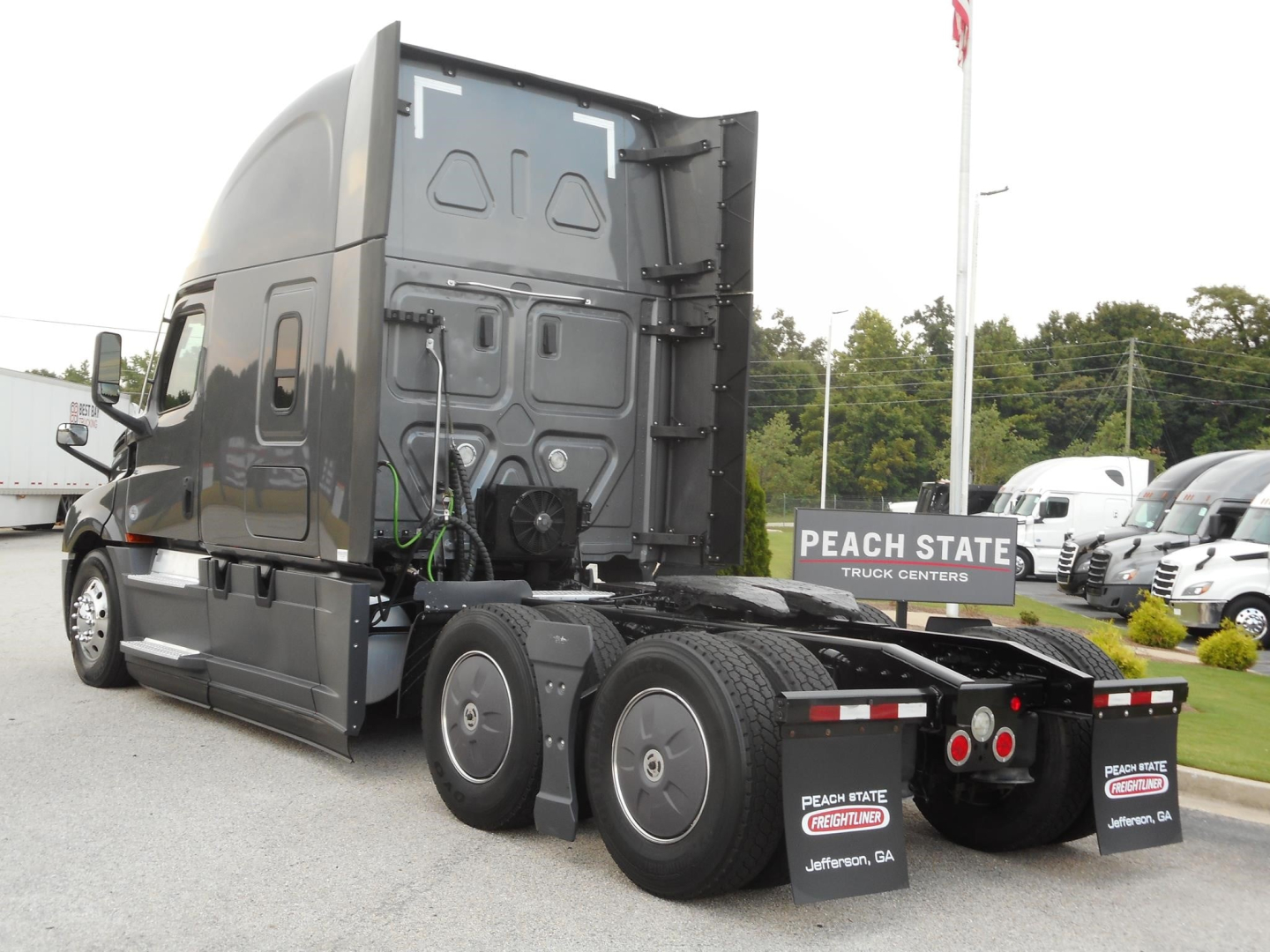 Freightliner Cascadia 126 sleeper cab side and rear showing dual rear axles and fifth wheel area with Freightliner truck dealership signage