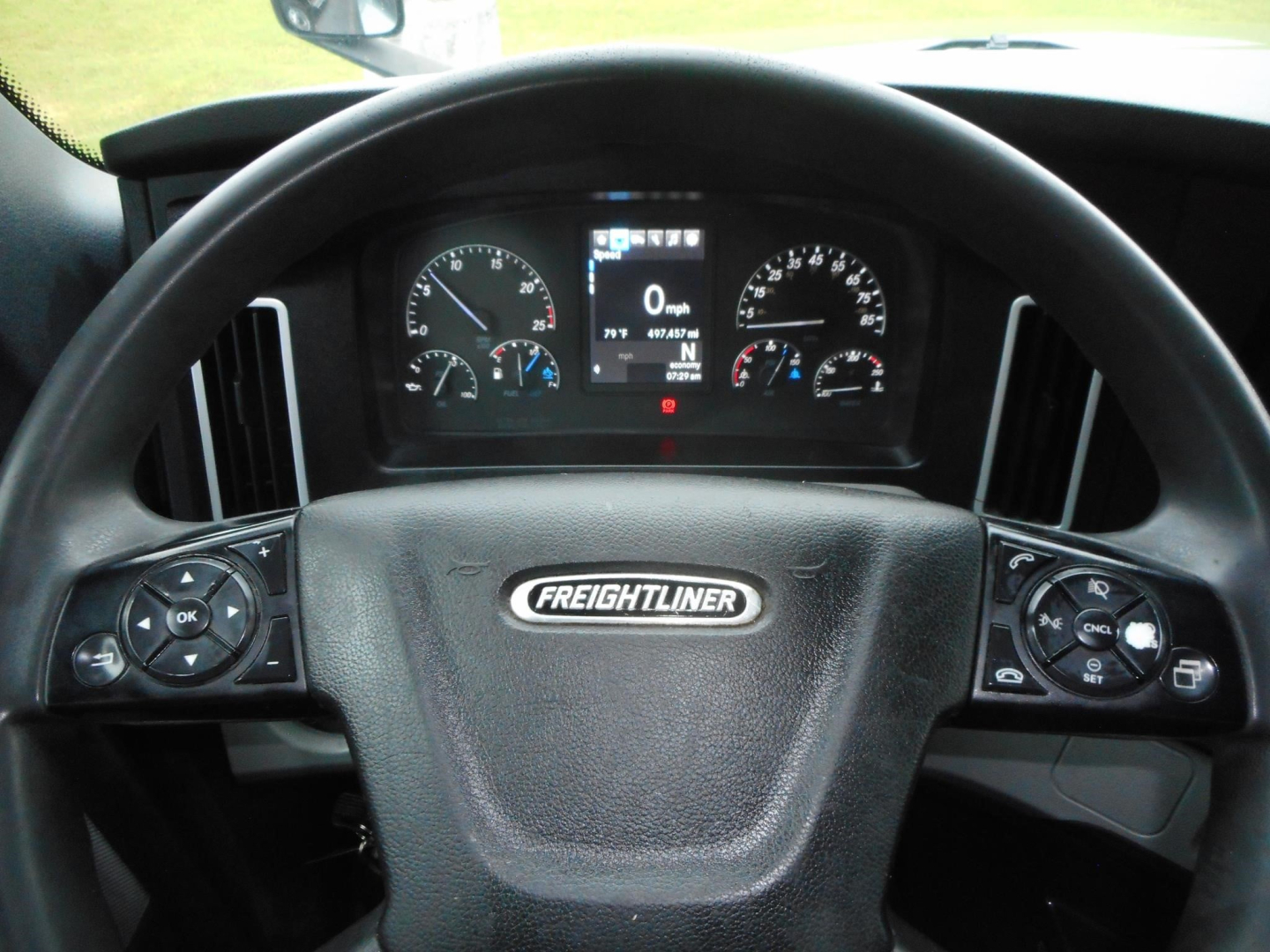 Steering wheel of a Freightliner Cascadia cabin showing instrument cluster and digital display behind the wheel.