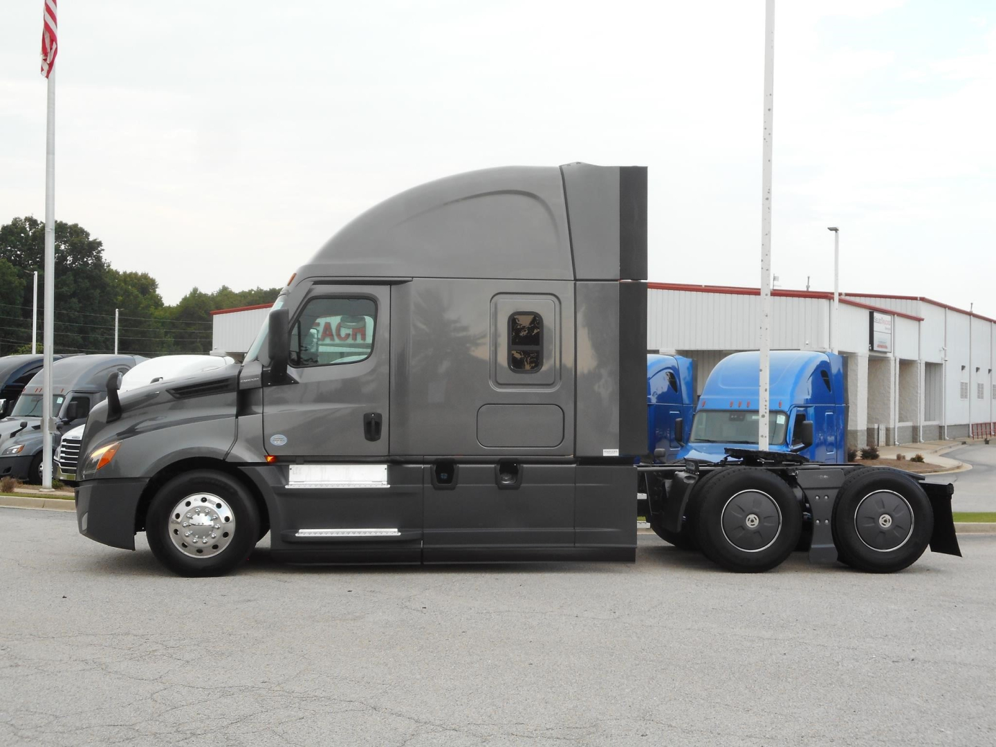Freightliner Cascadia 126 tractor side view showing sleeper cab, gray exterior, two fuel tanks, and chrome wheels.