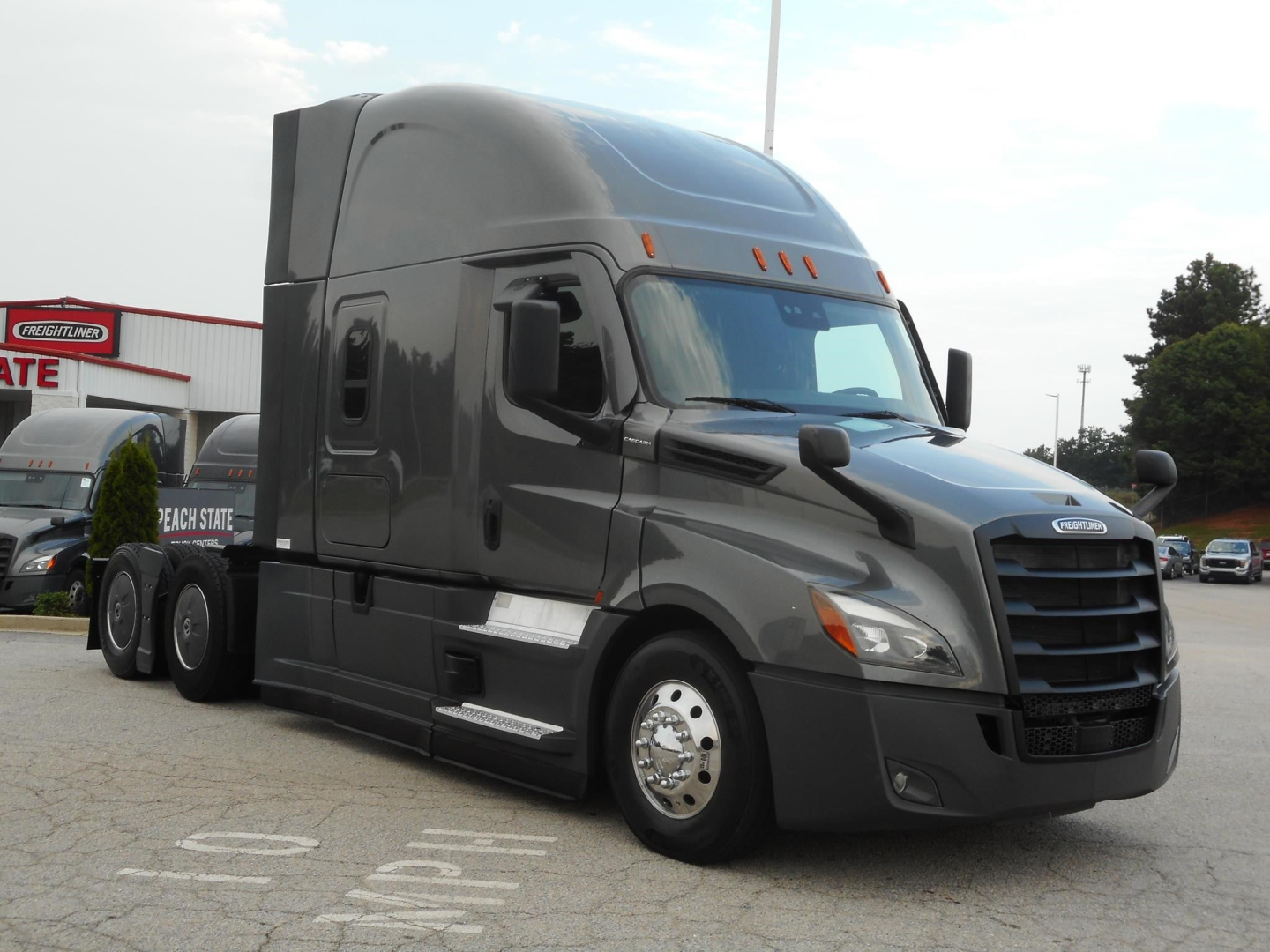 2022 Freightliner Cascadia 126 truck in dark gray, close view of cab with sleeper, front grille, and side mirrors.