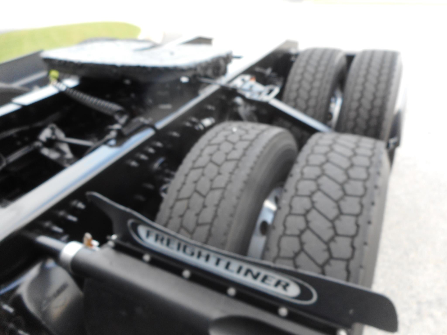 Freightliner truck chassis with dual rear axles and Freightliner badge visible on left side of frame.