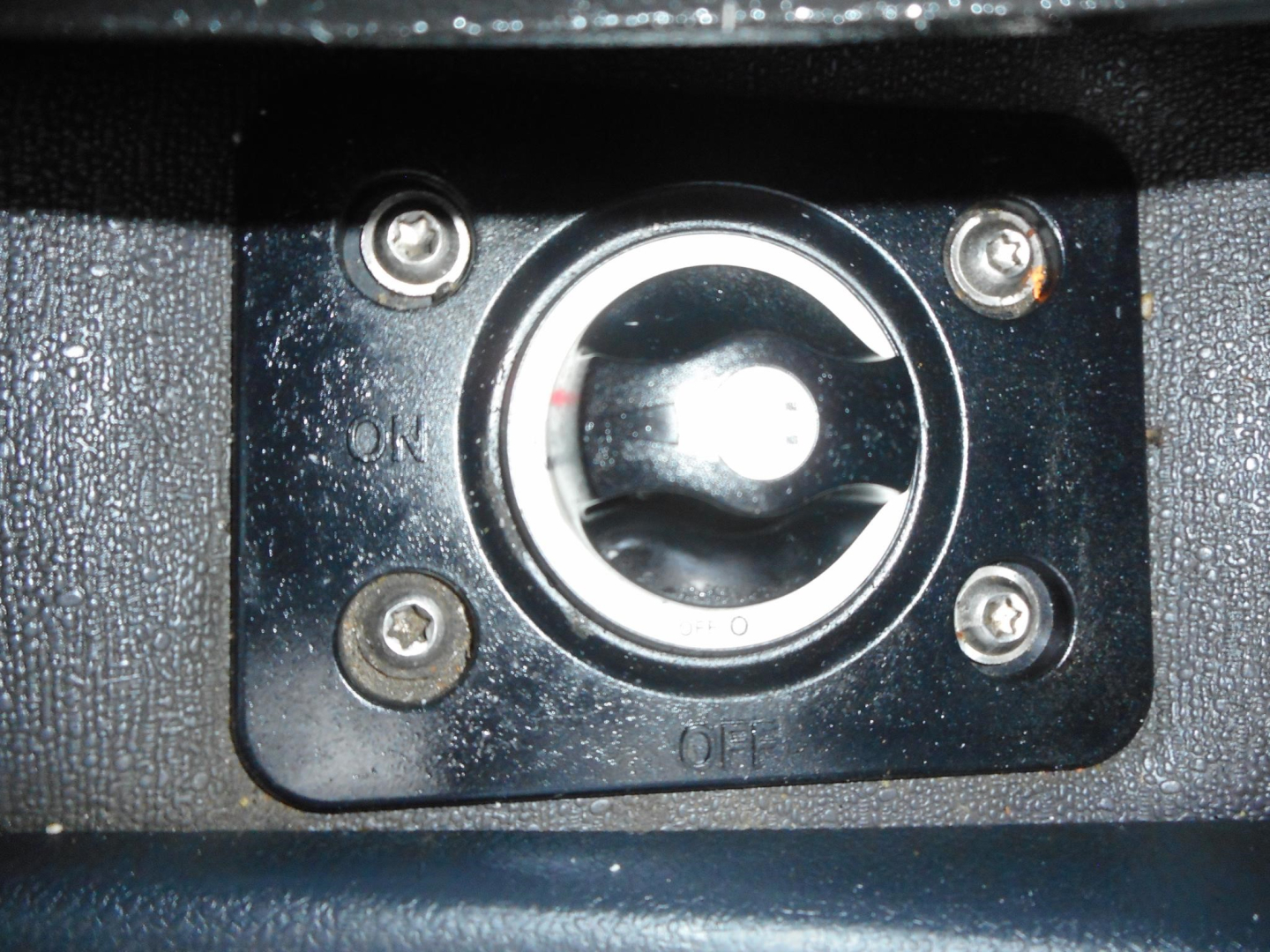 Truck cab interior showing key ignition switch with circular ring and four screws, labeled ON and OFF.