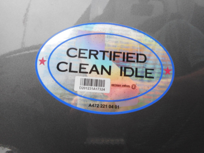 Fleet sticker on dark truck surface reading CERTIFIED CLEAN IDLE with holographic design and barcode sticker beneath.