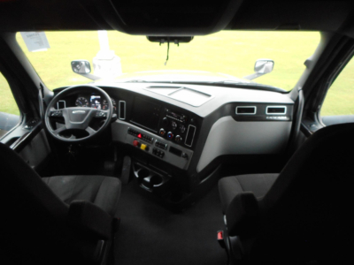 Truck cab interior view of a 2022 Freightliner Cascadia 126 showing steering wheel dashboard controls and center console.