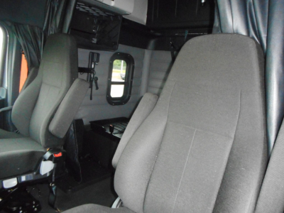 Interior cab seating area of a Freightliner Cascadia 126 truck showing front and side seats with storage compartments and window.