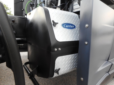 Carrier logo on the side of a pickup-style silver diamond-plate fuel tank mounted on a Freightliner Cascadia 126 truck engine area.