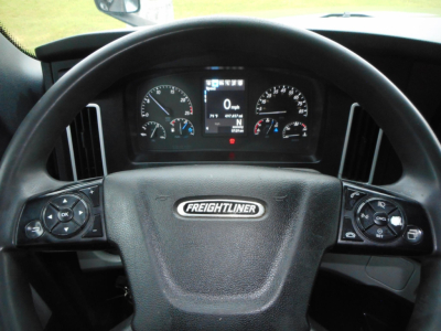 Steering wheel of a Freightliner Cascadia cabin showing instrument cluster and digital display behind the wheel.