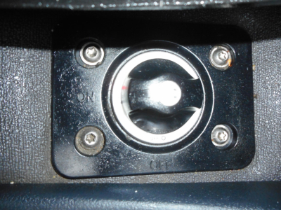 Truck cab interior showing key ignition switch with circular ring and four screws, labeled ON and OFF.