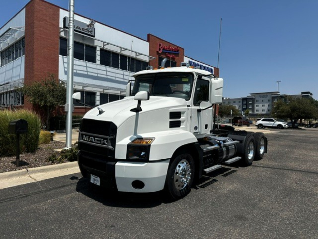 White 2020 Mack Anthem Conventional Daycab tractor in front of dealership showing Mack grille and fuel tanks.