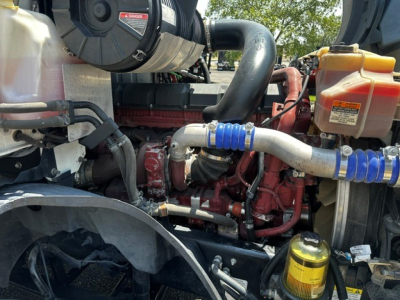 Engine bay of a 2020 Mack Anthem with visible hoses, coolant reservoir, oil filter, and diesel engine components.
