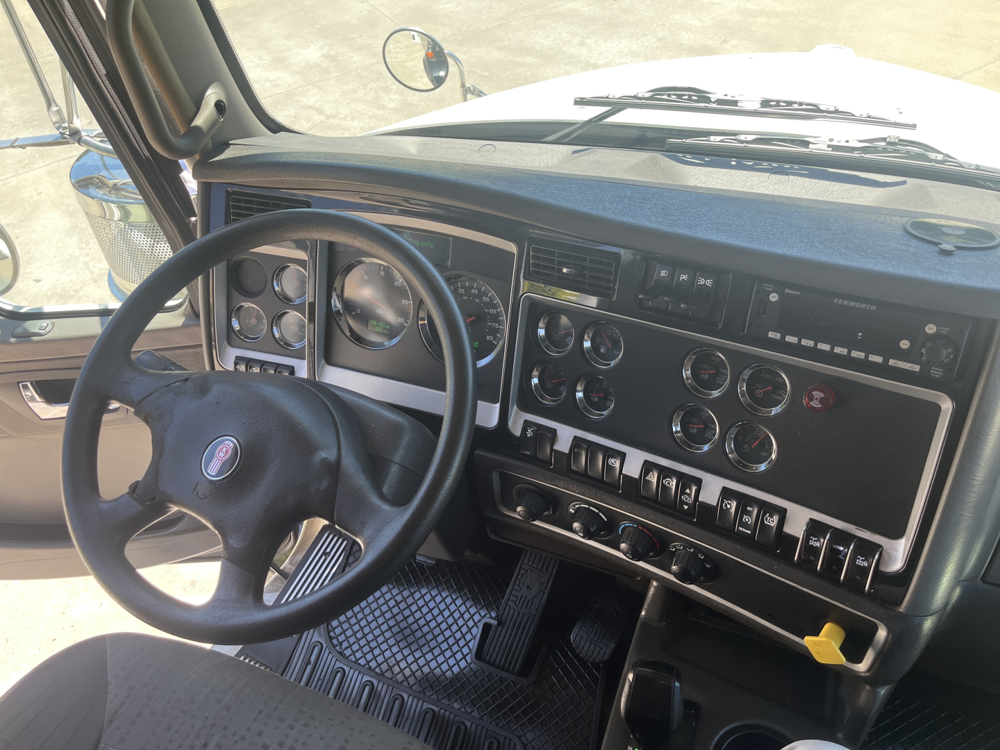 Truck dashboard and steering wheel from a Kenworth T800 cab interior showing instrument cluster, controls, and steering wheel with Kenworth emblem.