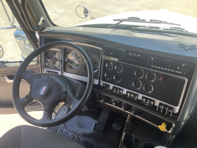 Truck dashboard and steering wheel from a Kenworth T800 cab interior showing instrument cluster, controls, and steering wheel with Kenworth emblem.