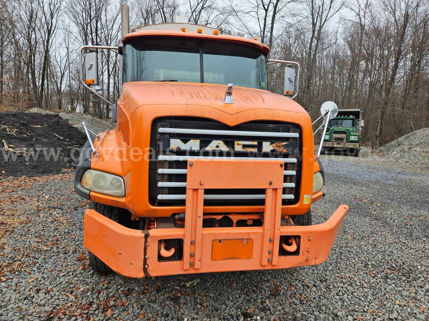 Front view of an orange 2009 Mack GU813 truck showing grille, bumper guard, headlights, and front mount; stock number and VIN not visible on text but the truck design is clear.