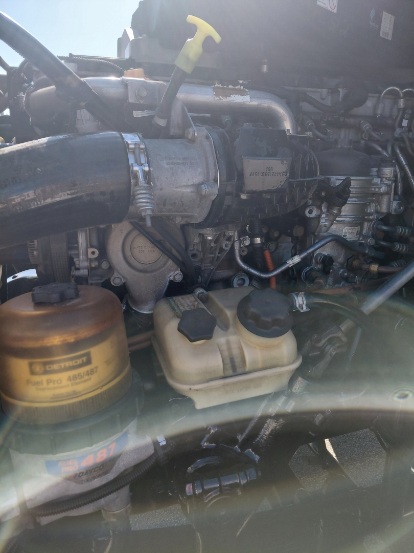 Engine bay of a Freightliner PT126064S showing coolant reservoir, hydraulic lines, and air intake tube.