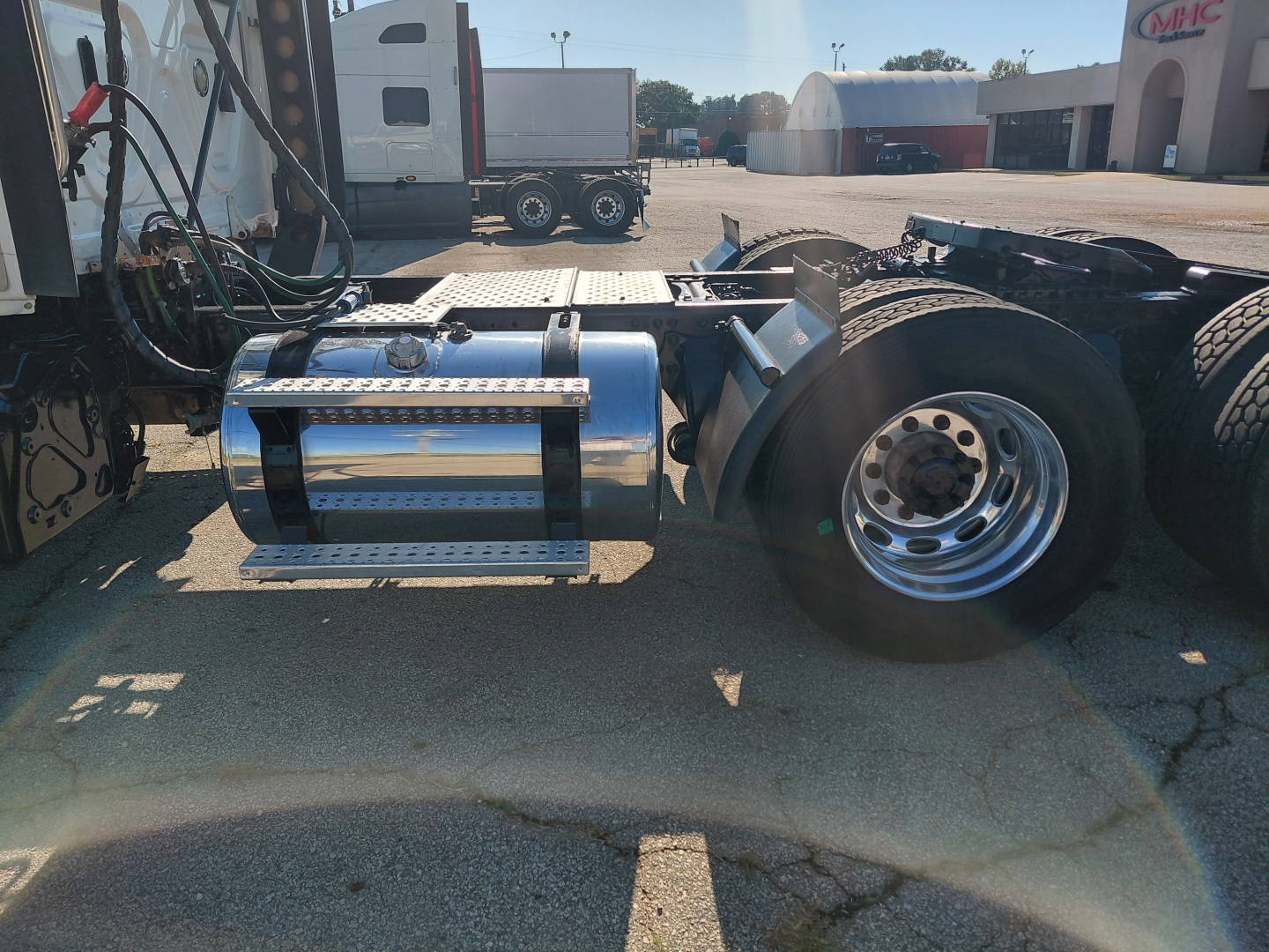 Truck chassis with chrome fuel tank and dual rear wheels showing undercab view; vocational heavy truck components visible.