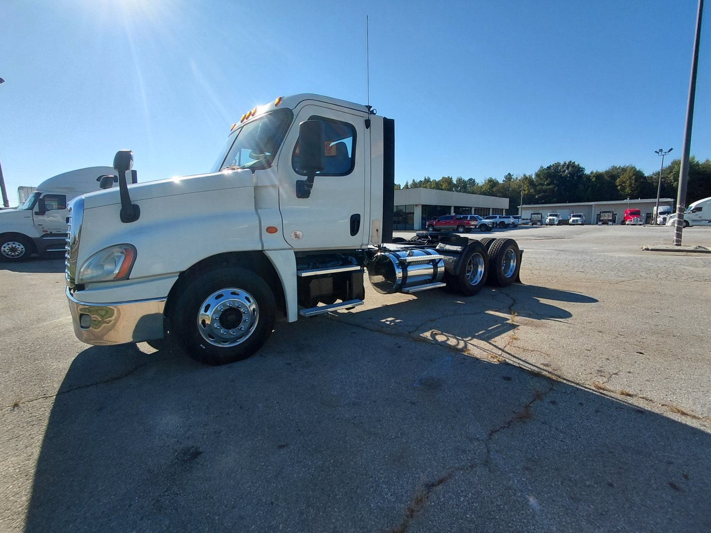 Truck chassis with cab in view showing Freightliner PT126064S T model, front left angle, 6x4 tractor missing trailer, VIN plate not visible, dealership lot in background