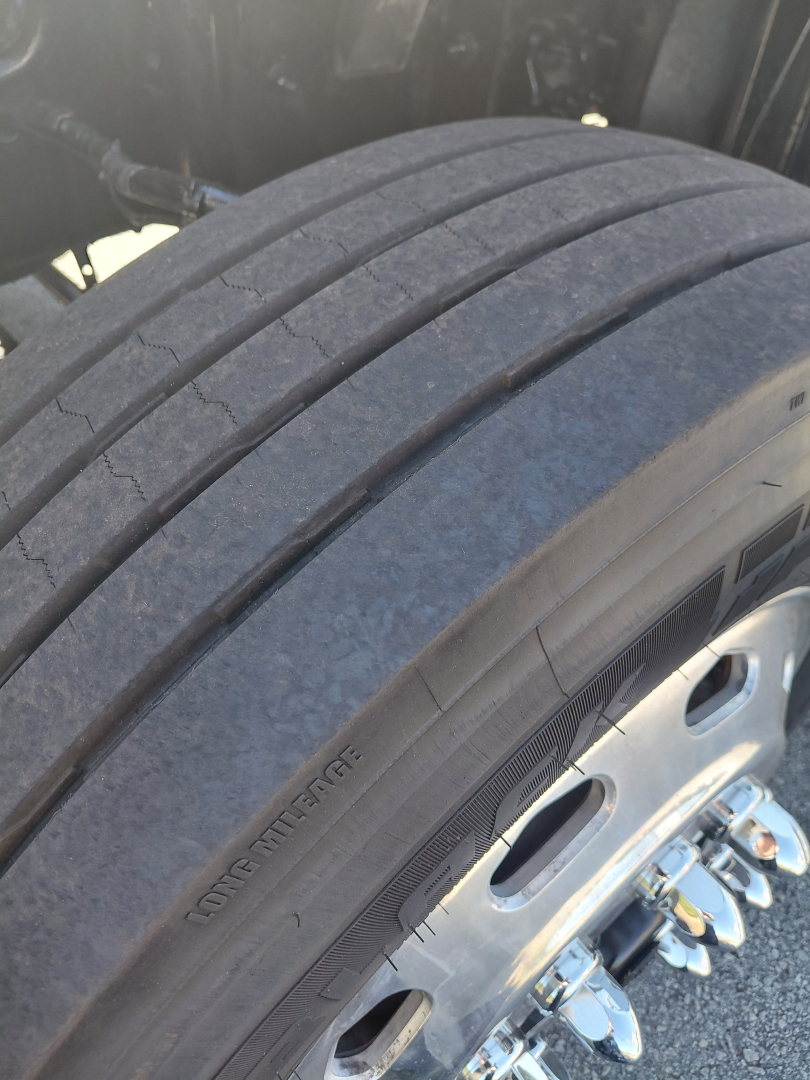 Tire and wheel view on Freightliner PT126064S sleeper truck, treaded tire with visible wheel lug nuts and hub area.