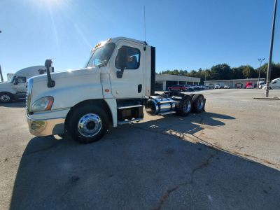 Truck chassis with cab in view showing Freightliner PT126064S T model, front left angle, 6x4 tractor missing trailer, VIN plate not visible, dealership lot in background
