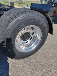 Goodyear rear tire on a Freightliner tractor showing Goodyear lettering and polished chrome wheel with lug nuts and hub.