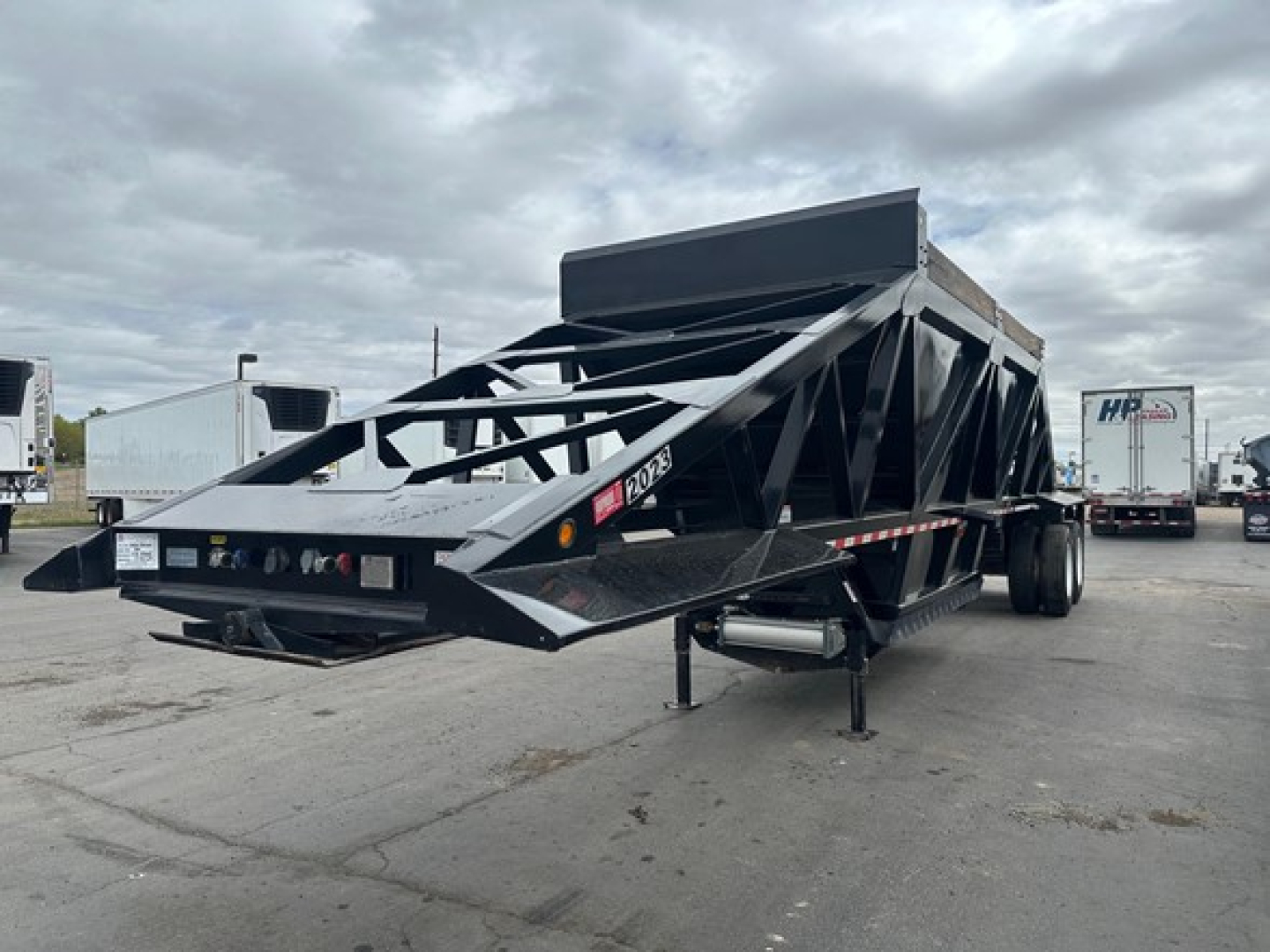 Trailer side view showing 2024 Brazos Air Ride Bottom Dump with black steel frame and high side panels; front hitch and landing gear visible.