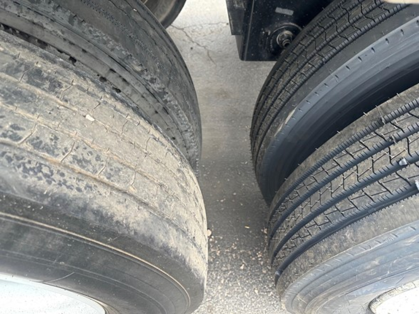 Tandem axle trailer tires with dirt and wear visible; close-up of wheel area on a Brazos air ride bottom dump trailer.