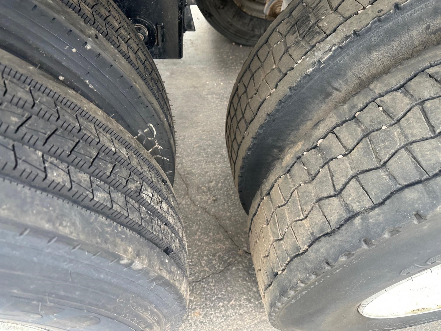 Trailer wheel close-up showing dual tires with tread pattern and wear, part of a Brazos bottom dump trailer.