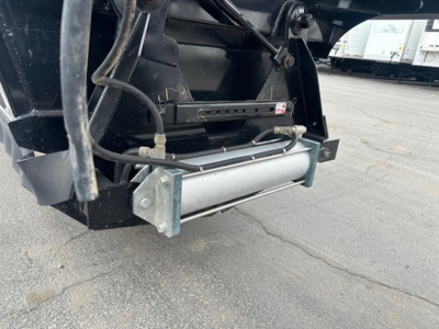 Bottom dump trailer hitch area showing hydraulic hydraulic cylinder and hoses attached to Braos/Brazos air ride system with metallic roller and mounting plates.