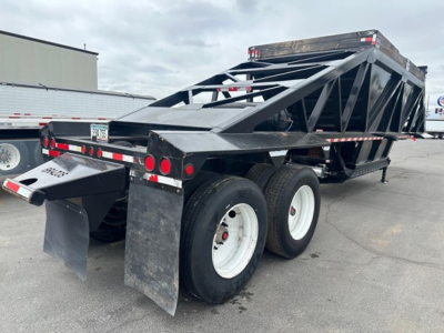 Bottom-dump trailer showing three axles and triangular lattice frame with black finish, rear mud flaps, and dump bed structure.