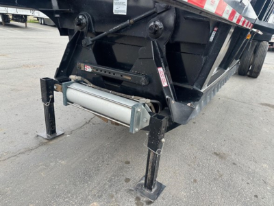 Bottom dump trailer undercarriage showing landing gear legs and hydraulic/roller mechanism with chrome cylinder and black frame