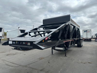 Trailer shows bottom dump semi-trailer with black steel frame and raised side walls; visible labels and lights on rear; loading area and support legs in foreground.