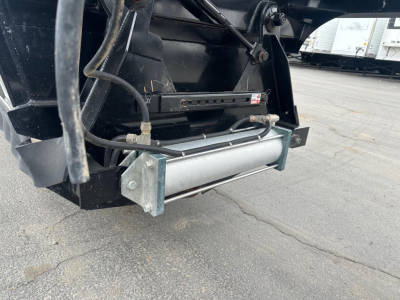 Bottom dump trailer showing hydraulic cylinder and underside hardware with trailer hitch and frame rails.