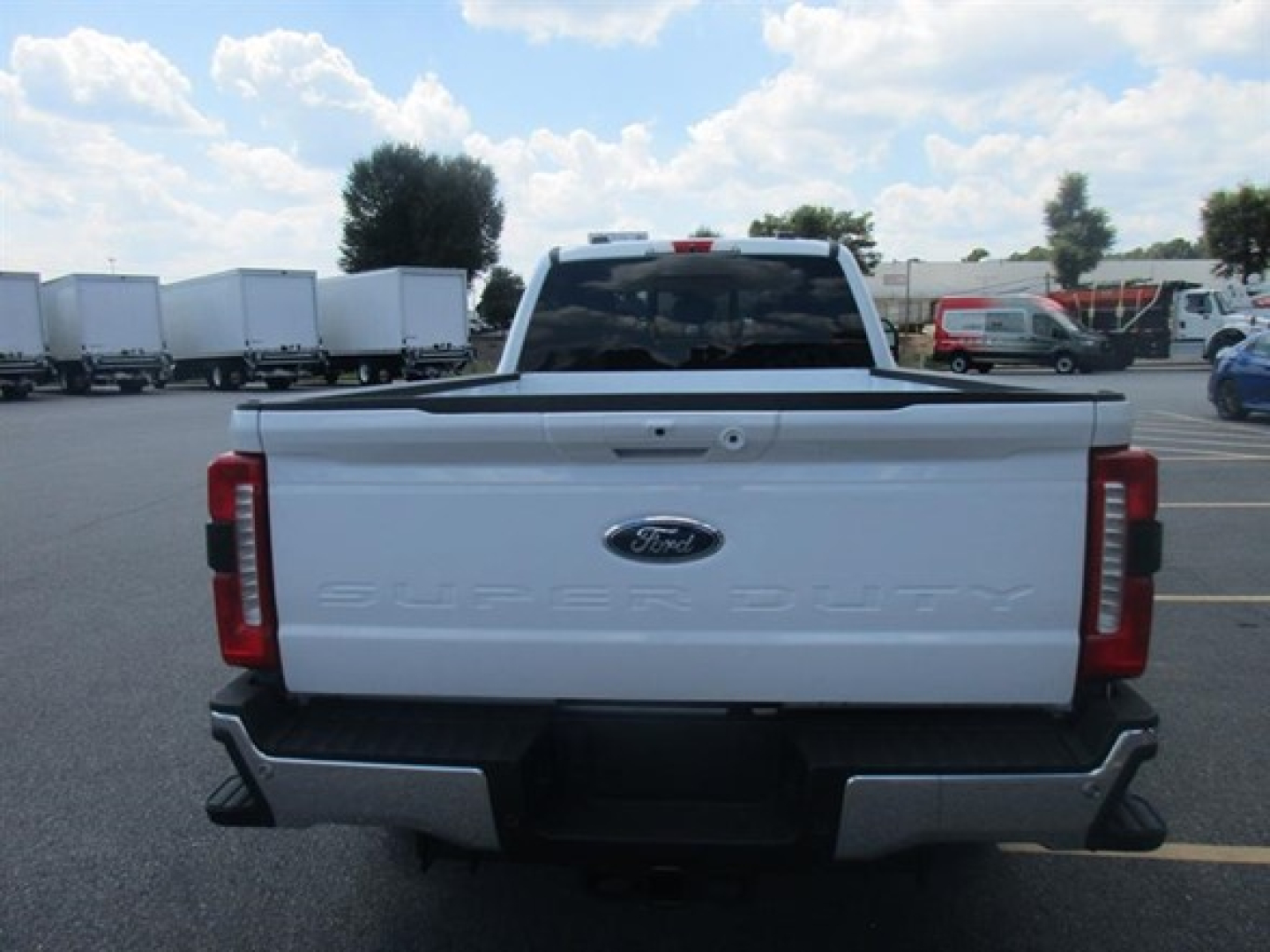 Ford F-250 Super Duty rear view showing tailgate with Ford emblem and embossed 'Super Duty' text in white model, truck bed in a parking lot.